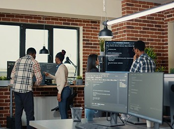 System Developers Analyzing Code On Wall Screen.